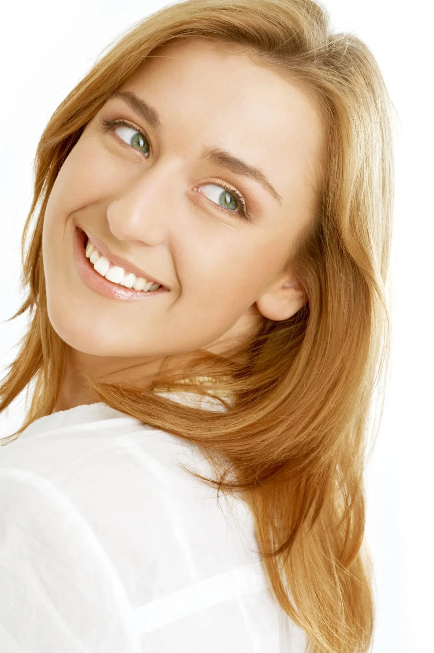 A person smiling over their shoulder, showing straight white teeth.