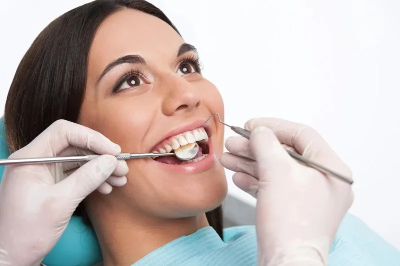 A dentist examining a patient's teeth with a mouth mirror and dental probe.