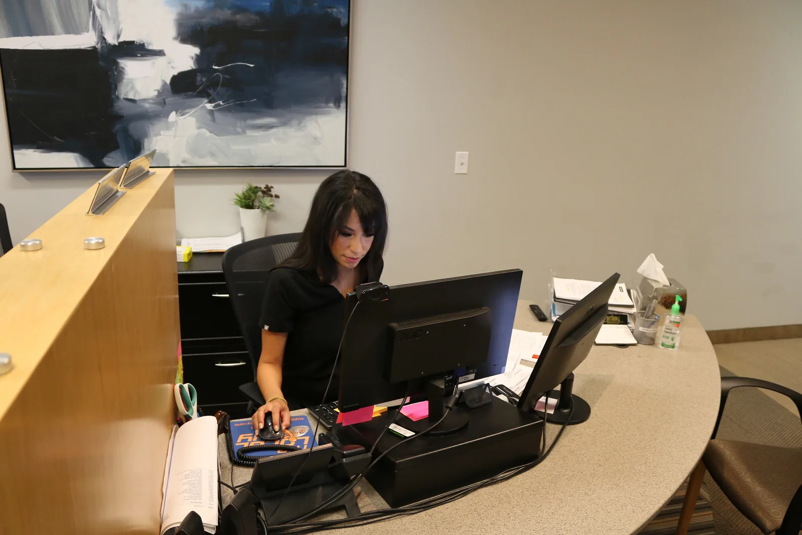 A staff member sitting at a front reception desk working on a computer.